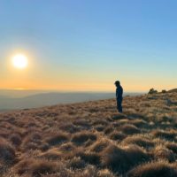 man hiking over grassy terrain at sunset in Istria