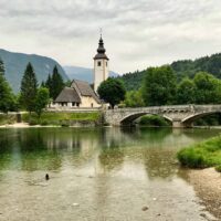 white church and stone bridge near lake bohinj slovenia
