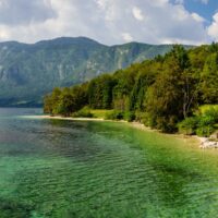 blue green lake bohinj surrounded by mountains in slovenia