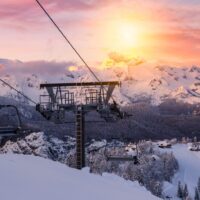 ski lift and snow covered mountains at sunset