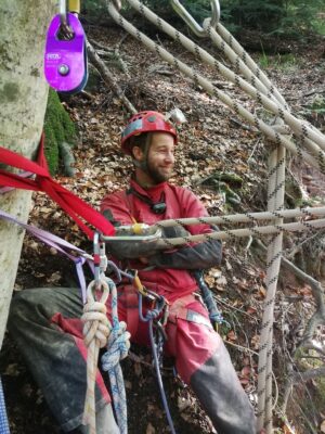 man in red caving gear with ropes and other safety equipment